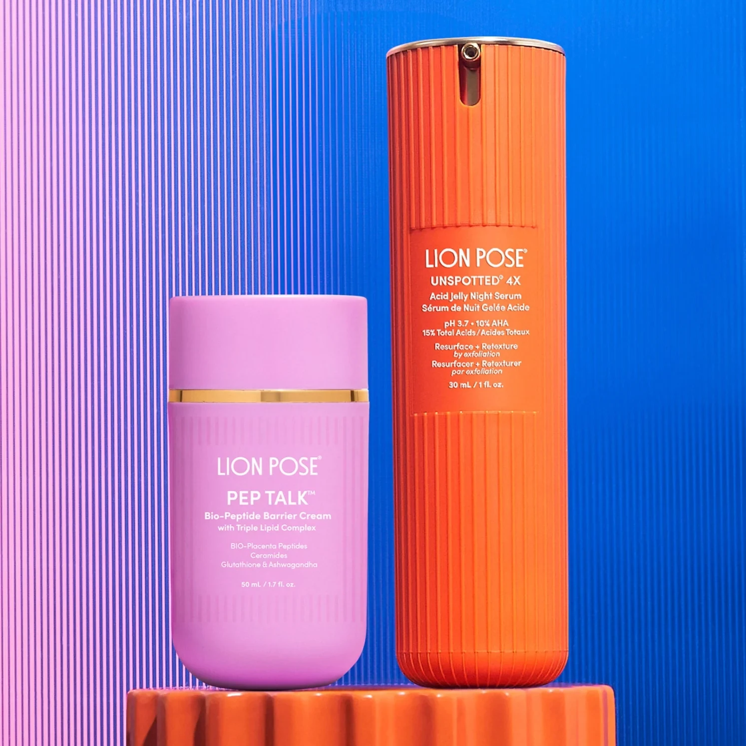 Lion Pose PEP TALK cream jar beside the UNSPOTTED serum bottle on an orange plinth